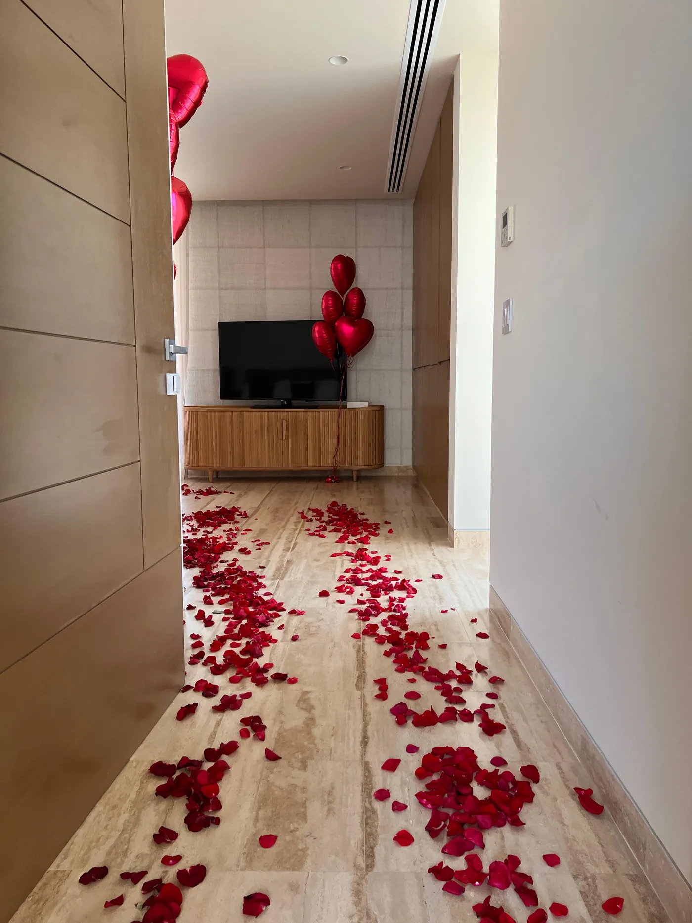 Rose petal path leading into a hotel suite with red heart balloons