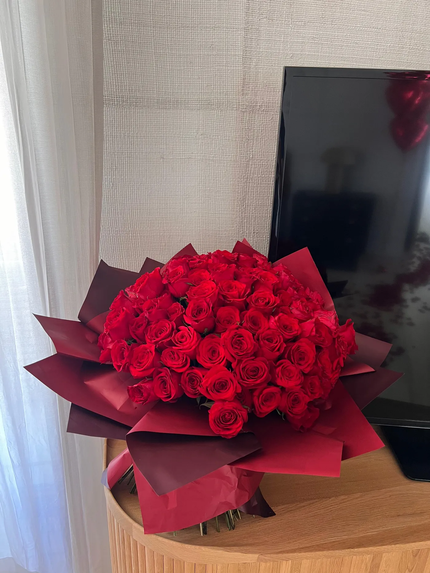 Large bouquet of red roses in burgundy wrapping delivered to a hotel room
