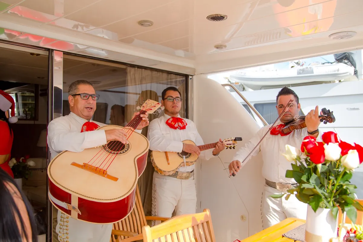 Mariachi trio in white suits playing guitar, vihuela and violin on the deck of a yacht