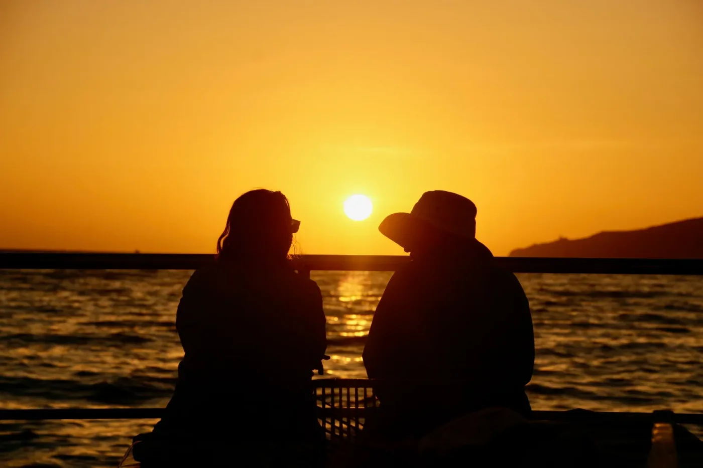 A couple sitting together on the boat watching the sun set over the water off Cabo San Lucas